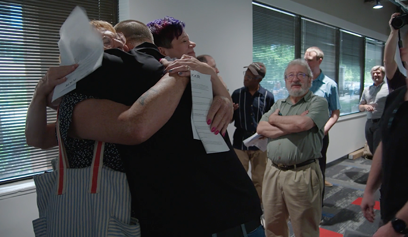 Employees at RB Media embrace in celebration.